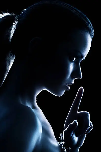 Young woman showing quiet handsign. Dark blue silhouette.