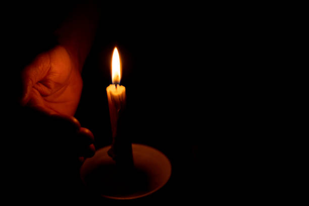 istock candle flame illuminates a female hand in a dark room 1521418268