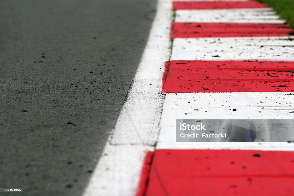 Race Track Kerb with Rubber Debris A brightly painted red and white kerbing edges a smooth tarmac race track. Rubber tyre debris is scattered across the track and kerbs. Shallow depth of field with focus on the second and third stripe. Silverstone Stock Photo