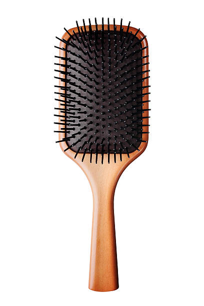 A bristled brown hair brush against a white background Image of a paddle hair brush with wooden handle and flexible black bristles, photographed on white background. hairbrush stock pictures, royalty-free photos & images