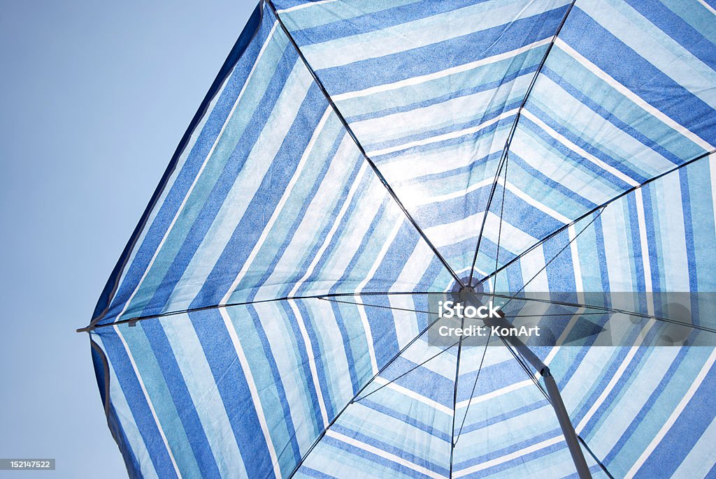 Blue Backlit Parasol Against Plain Sky Umbrella at the beach Holiday Background Beach Umbrella Stock Photo