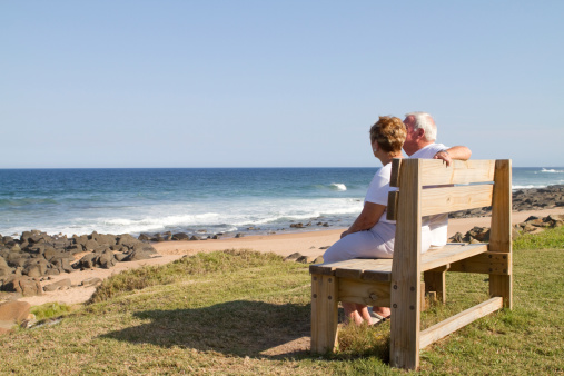 rear view of senior couple sitting on beach bench