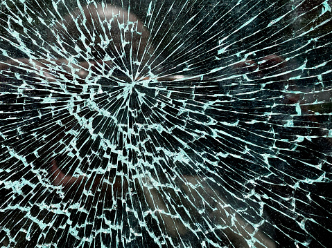 Broken glass in a plastic window in a house, on a green background. Broken glass, cracks in the glass.