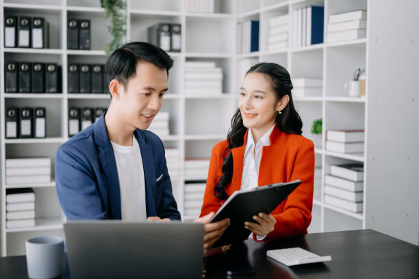 istock Asian business colleague business presents and explains and using laptop and tablet. Teamwork, financial marketing team, while sitting in home office room. 1521488258
