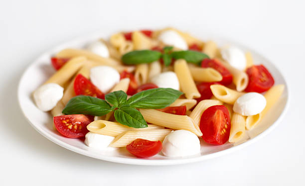 penne pasta und salat caprese - vibrant color tomato vegetable pasta stock-fotos und bilder