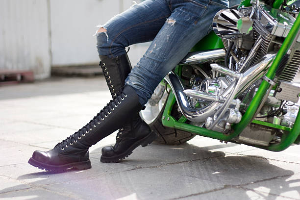 verde motorcycle y una mujer en altas fundas cerca de ella. - chromeplated fotografías e imágenes de stock