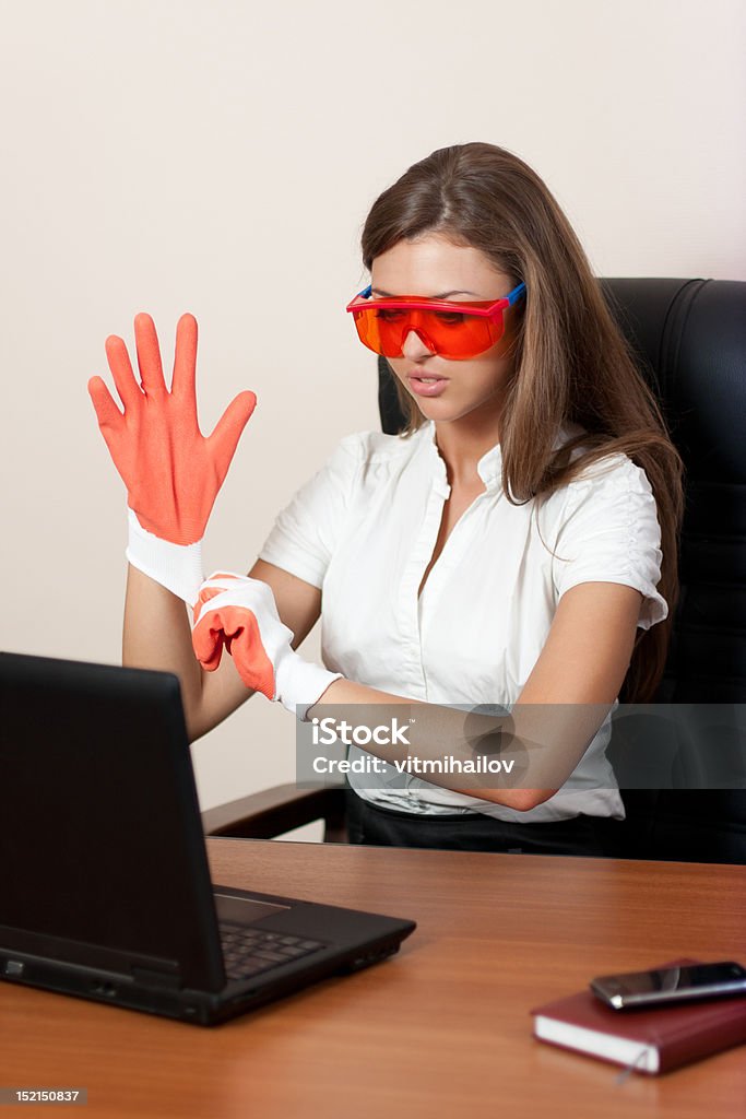 Giovane donna con il portatile in guanti e occhiali arancione - Foto stock royalty-free di Adulto