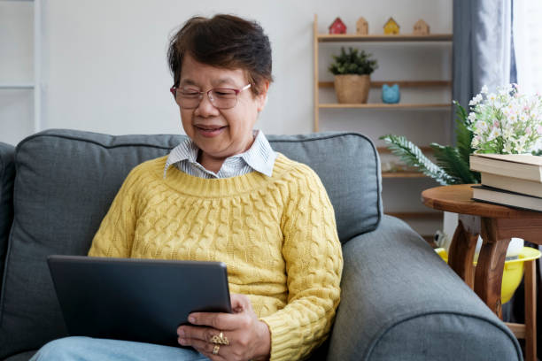 istock Mature Asian Woman Using Digital Tablet Sitting At Home 1521514431