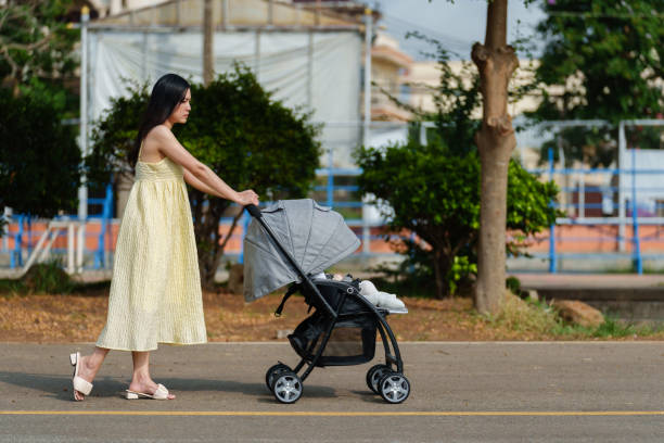 istock mother pushing infant baby stroller and walking in park 1521517505