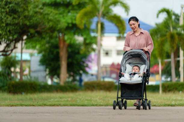 istock happy mother pushing infant baby stroller and walking in park 1521517521