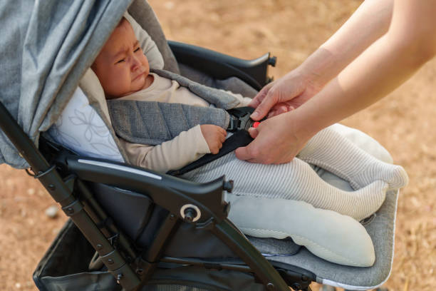 istock woman fastening belt on stroller with crying baby 1521518556