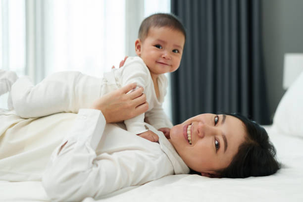 istock happy mother lying and playing with her infant baby on bed 1521527290
