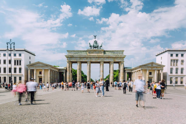 Dynamic crowd, Brandenburg Gate, Berlin, daytime, bustling city, blurred motion, lively atmosphere.