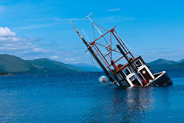 Fishing vessel partially submerged in Loch Linnie Lake A foundered and partially submerged fishing vessel or samon farm support vessel in Loch Linnie just north of the village of Ardgour at 56°43`35.36" N  5°15`52" W fishing boat sinking stock pictures, royalty-free photos & images