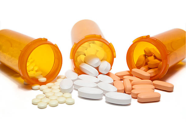 Three orange prescription bottles spilling different pills Three spilled bottles of prescription medication.  File sizes up to XXXL available. statin photos stock pictures, royalty-free photos & images