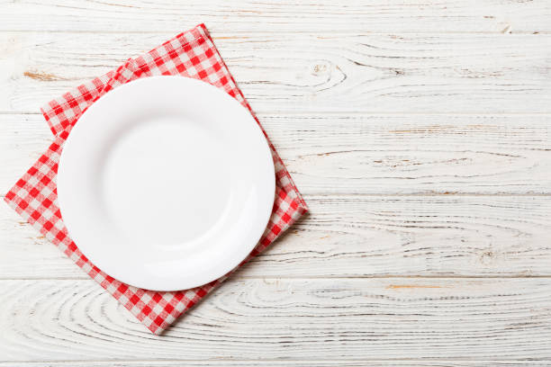 istock Top view on colored background empty round white plate on tablecloth for food. Empty dish on napkin with space for your design 1521602482