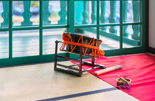 Japanese shime-daiko drum with bachi sticks next to a kane or chanchiki mini gong on a tatami.