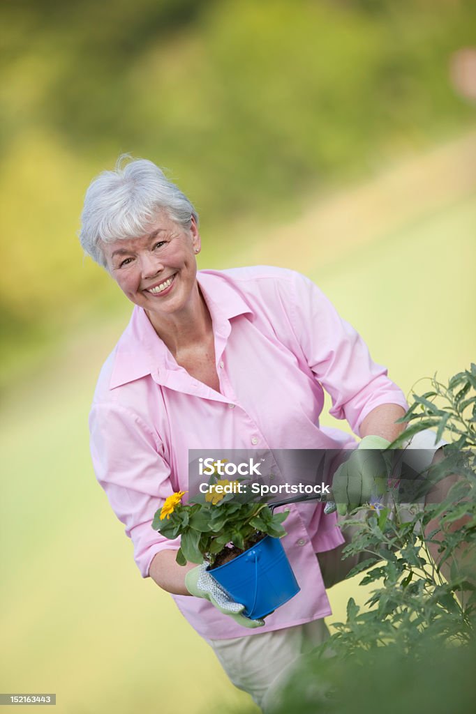 Senior Lady divertirsi nel giardino di fiore - Foto stock royalty-free di 60-69 anni