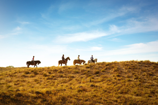 horseback riding in the dunes near a beach at sunset