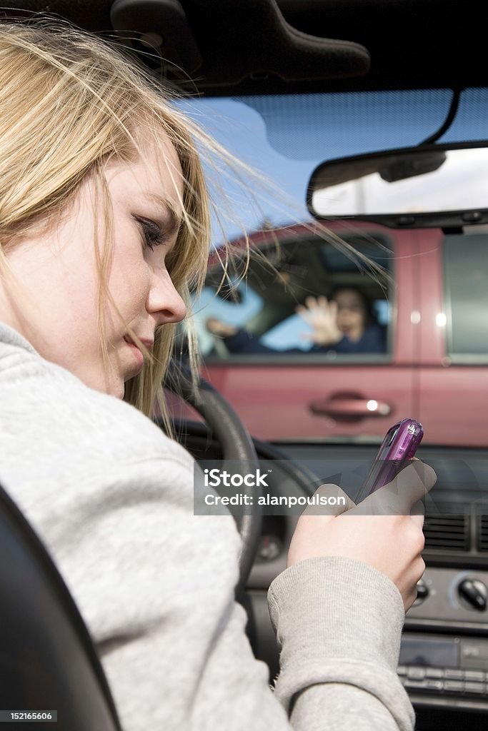 Girl texting accident A teenager texting on her phone and looking away from the road where she is about to hit a truck with a woman in the drivers seat. Driving Stock Photo