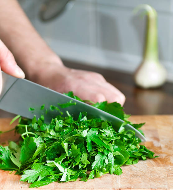 Closeup of cook's hands chopping green herbs with knife stock photo