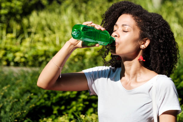 istock Curly woman drinking aloe vera in a park. 1521670119