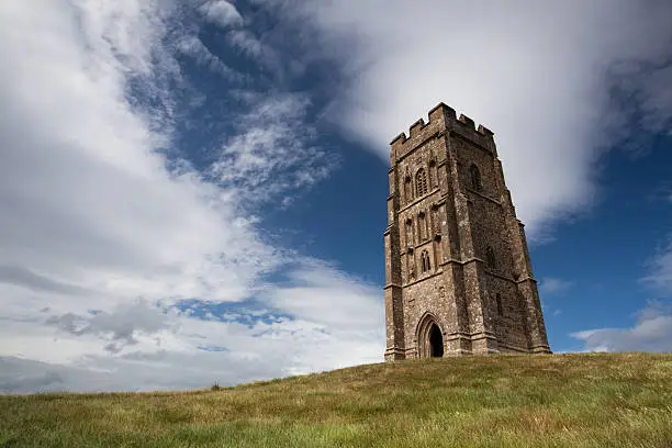 Tourists exploring the ruins of St. Michael's Tower at the top of glastonbury tor in somerest england