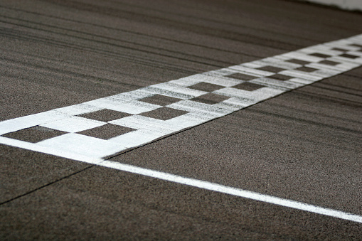 The painted start/finish line across the track at the Rockingham motor speedway in Northamptonshire, UK. Black tire marks are streaked across the track. 