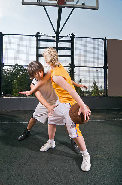 Teenagers playing basketball Two teenagers playing one-on-one at the streetball playground teenager couple child blond hair stock pictures, royalty-free photos & images