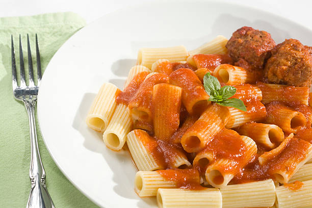 Rigatoni and Meatballs Rigatoni pasta and Meatballs dinner. Topped with basil garnish. penne meatballs stock pictures, royalty-free photos & images