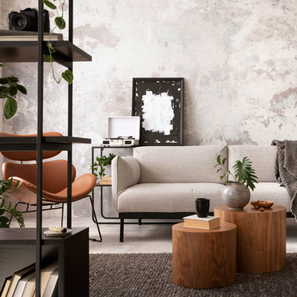 istock Modern composition of indiustral living room interior with mock up poster frame, gray sofa, round wooden coffee table, brown leather armchair, black desk, modern lamp, rack and personal accessories. Home decor. Template. 1521737011