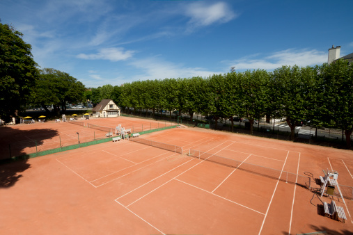 tennis coach is taking tennis ball on clay court focus on foreground horizontal still