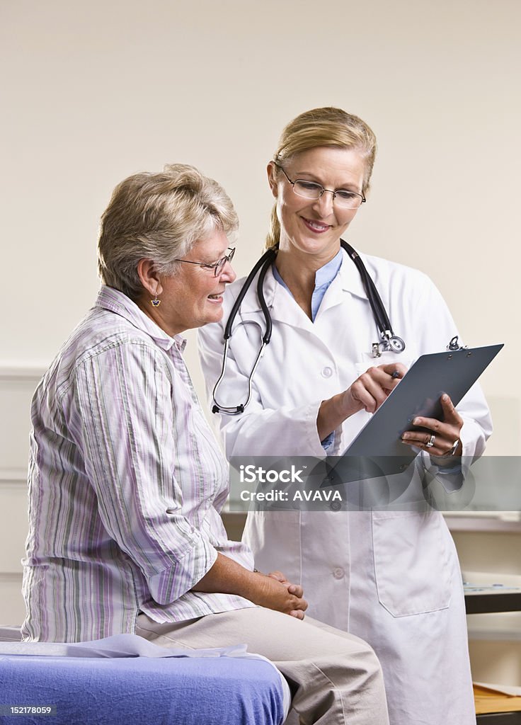 Medico spiegando medicina per donna anziana tabella - Foto stock royalty-free di Medico