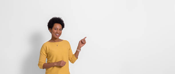 smiling businesswoman pointing away at copy space for advertisement isolated on white background - boegbeeld model stockfoto's en -beelden