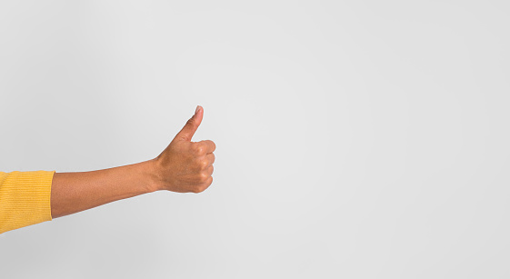 Cropped hand of positive businesswoman showing thumbs up sign against white background