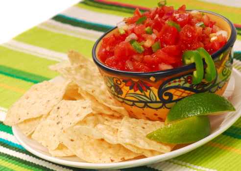 Freshly made tortilla chips with a corn and tomatoe salsa with limes