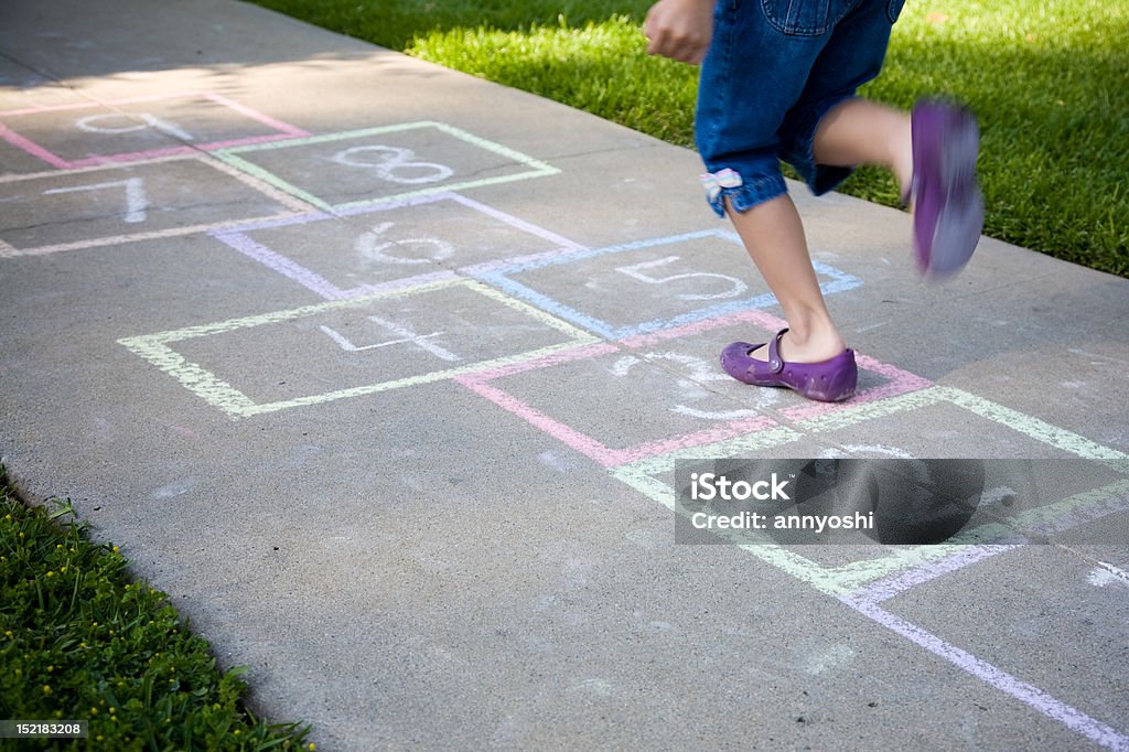 Una giovane ragazza giocare Gioco della campana su un marciapiede - Foto stock royalty-free di Gioco della campana