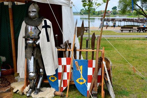 Kyiv, Ukraine. July 06, 2013. Two knights are fighting in armor with swords, reconstruction of the tournament. A scene with spectators from a log house. Celebration of the pagan day of Ivan Kupala