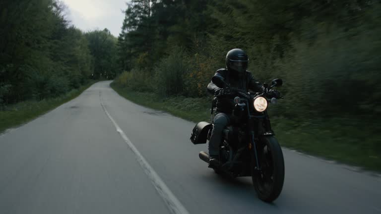 Male riding speed fast a vintage motorbike on a forest road.