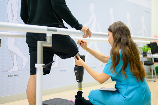 Physiotherapist adjusting prosthetic leg of patient in hospital, Disabled patient with treatment at health care center, New artificial limb production for disabled people