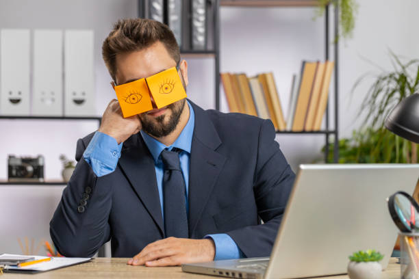 istock Inefficient tired lazy business man working sleeping on laptop computer with eyes stickers on face 1521871008