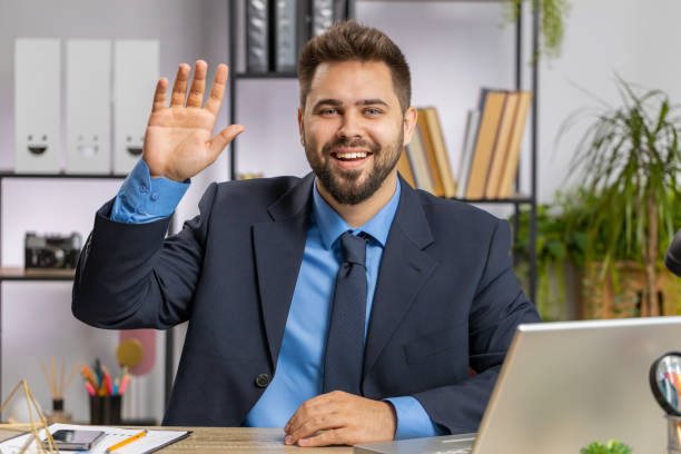 istock Businessman working on laptop smiling friendly at camera and waving hands gesturing hello at office 1521871021