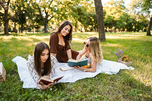 Three bestfriends reading books on a picnic date in the park