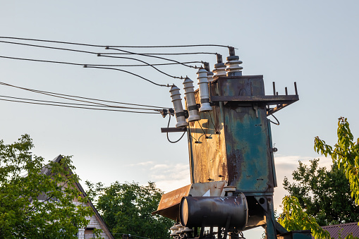 Old big electric transformer with wires close-up outdoors on a summer sunny day