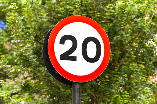 Road sign marking the start of a 20 mph speed limit zone in a residential area. No people.