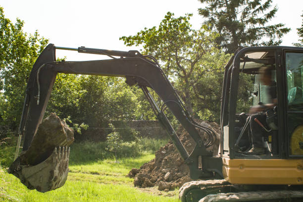 istock a mini digger carries a large stone in its bucket 1521900645
