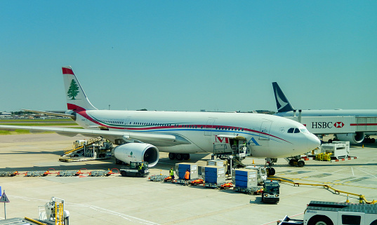 London, England, UK - 14 June 2023: Airbus A330 passenger jet (registration OD-MEC) operated by MEA Middle Eastern Airways parked at one of the terminals at Heathrow airport. Air cargo equipment is alongside the plane.