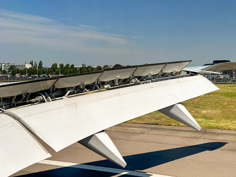 London, England, UK - 14 June 2023: Wing of a large passenger jet with flaps down and air brakes open to slow down on landing at a London airport.
