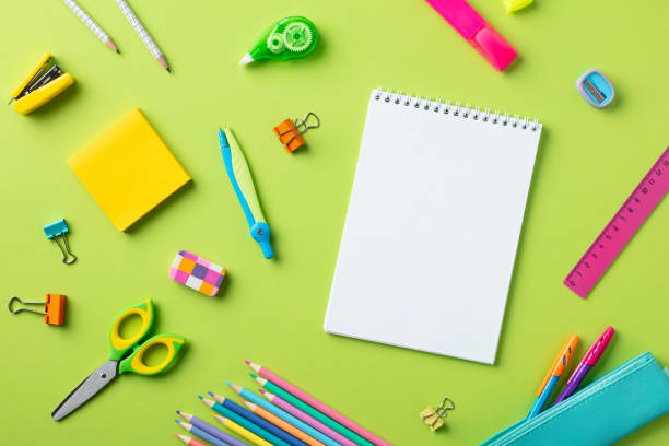 Back to school concept. Flat lay blank paper notepad with school supplies on green background