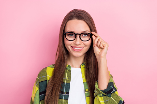 Portrait of pleasant smart girl with straight hairdo wear plaid shirt hand hold eyewear at checkup isolated on pink color background.